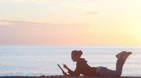 Woman using a tablet on the beach during sunset Video stock 61438367