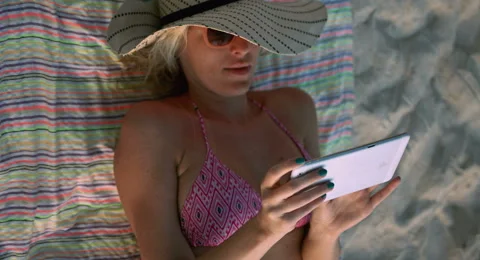 Woman Using a Tablet at the Beach Stock Footage 61157721