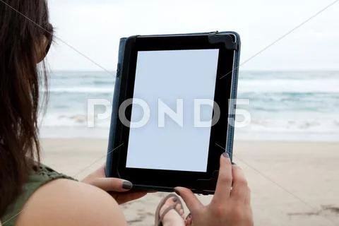 Woman using tablet on beach Stock Photos