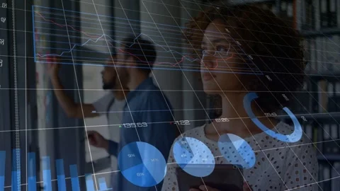Woman using tablet checking data as man writing on glass, overlay appearing Stock Footage 333078141