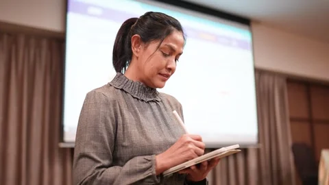 Woman using tablet computer and digital pen in front of stage of show room at wo Stock Footage 256974274