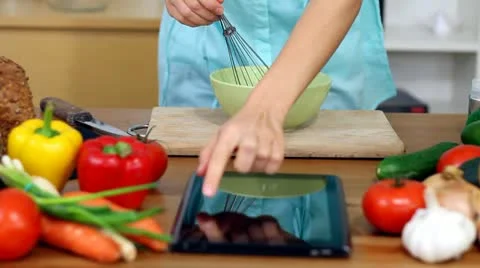 Woman using a tablet computer to cook in her kitchen Stock Footage 8983812