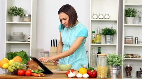 Woman using a tablet computer to cook in her kitchen Stock Footage 8983827