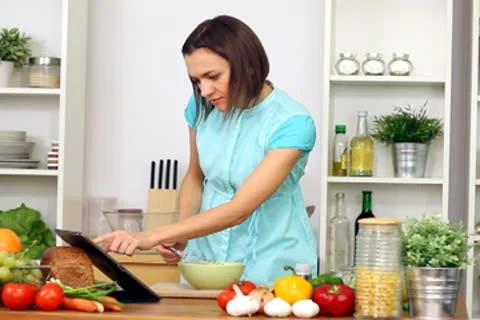 Woman using a tablet computer to cook in her kitchen Stock Footage 8983829