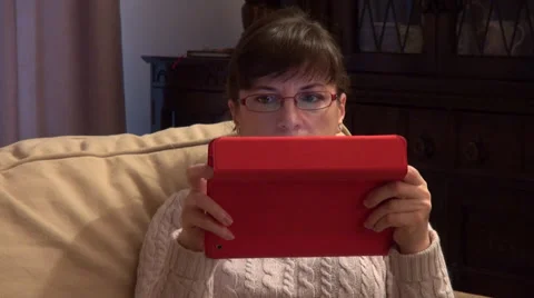 Woman using a tablet computer on a couch at home, reflection in eyeglasses Stock Footage 34651084