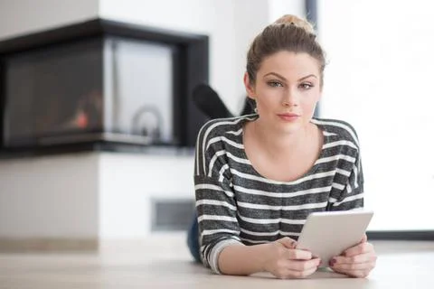 Woman using tablet computer in front of fireplace beautiful young woman we... Stock Photos