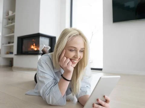 Woman using tablet computer in front of fireplace beautiful young woman su... Stock Photos