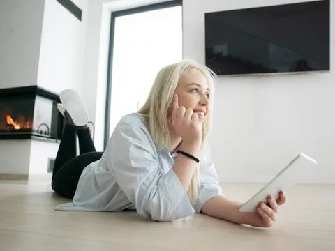 Woman using tablet computer in front of fireplace beautiful young woman su... Stock Photos