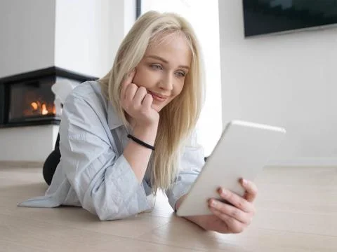 Woman using tablet computer in front of fireplace beautiful young woman su... Stock Photos