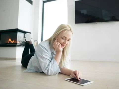 Woman using tablet computer in front of fireplace beautiful young woman su... Stock Photos