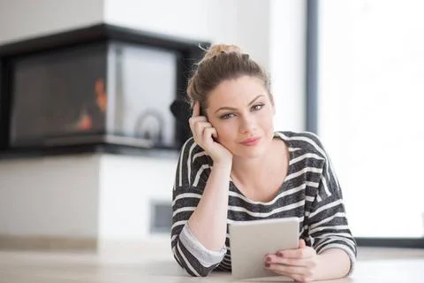 Woman using tablet computer in front of fireplace beautiful young woman we... Stock Photos