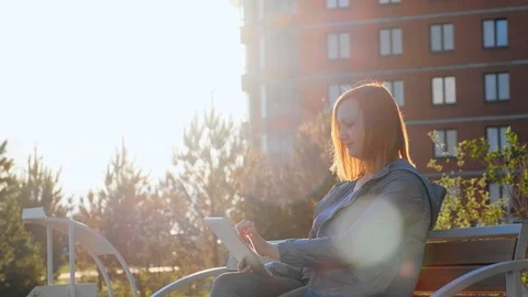Woman using tablet computer sitting on bench in city Stock Footage 111004204