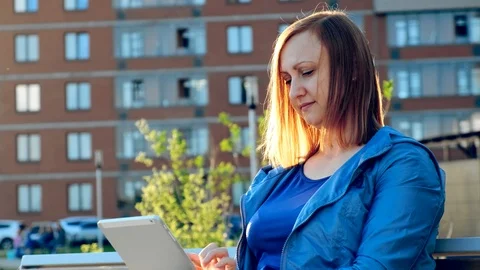 Woman using tablet computer sitting on bench in city Видео 111183692