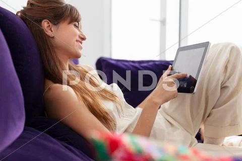 Woman Using Tablet Computer On Sofa