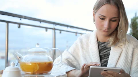 Woman using tablet computer touchscreen, drinking tea in cafe 库存影片 67511999