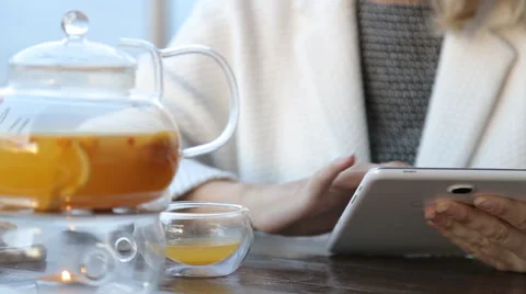 Woman using tablet computer touchscreen, drinking tea in cafe Stock Footage 67512022