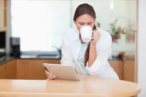Woman using a tablet computer while drinking coffee 스톡 사진