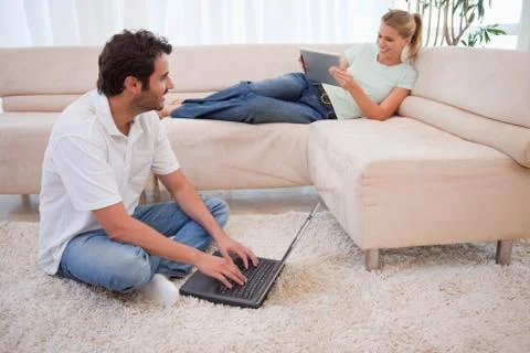 Woman using a tablet computer while her fiance is using a laptop 스톡 사진