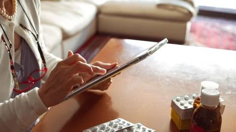 Woman using a tablet to order medications online or check prescriptions Stock Footage 274676746