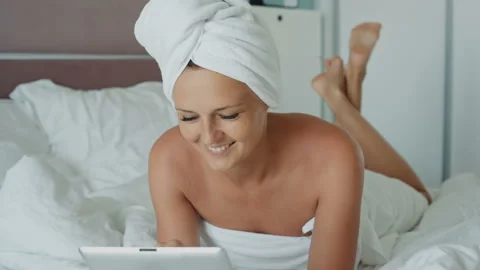 Woman using tablet PC after shower and smiling in hotel room Stock Footage 101191853