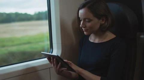 Woman using Tablet PC next to Window in Moving Train Stock Footage 56435161