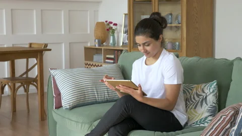 Woman Using Tablet PC on Sofa at home. Bright And Cozy Room Stock Footage 141008459