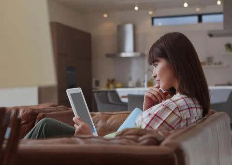 Woman using a tablet PC on a sofa Foto stock