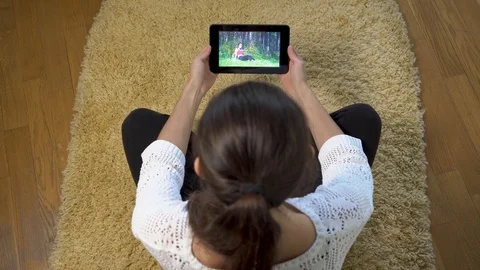 Woman using tablet pc for watching sport training on screen while sitting at Stock Footage 97894123