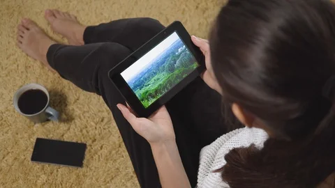 Woman using tablet pc for watching nature and vacation video on screen while Stock Footage 97894590