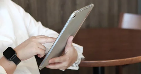 Woman using a tablet with a smartwatch in a cafe, remote work, digital tech.. Stock Footage 340607092