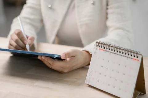 Woman using tablet, technology, digital pen to plan schedule with desk cale.. Stock Photos