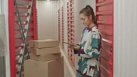 Woman Using Tablet while Leaving Boxes in Self Storage Stock Footage 259827156