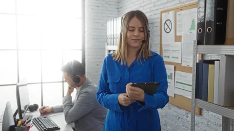Woman using tablet while man works at computer in bright, modern office, bo.. Stock Footage 304925942