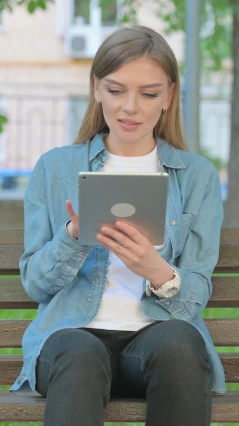 Woman Using Tablet while Sitting on Bench in Park, Vertical Video Video stock 319007748