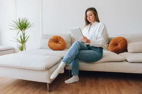 Woman Using Tablet While Sitting on Sofa 스톡 사진