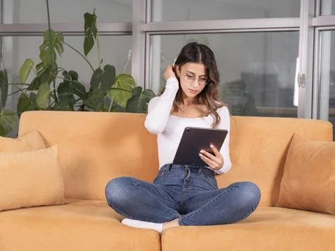 Woman using tablet working on couch at home in living room. Stock Photos