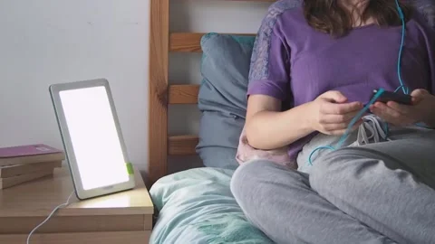 Woman using technology (light therapy lamp, smartphone) for mental healthcare Stock Footage 222000744