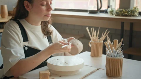 Woman Using Tool to Apply Pattern to Clay Cup in Sunlit Workshop Stock Footage 331807568