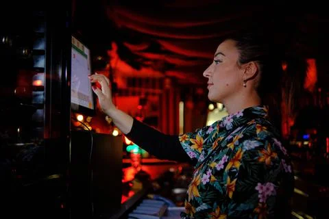 Woman using touch screen computer while working behind the counter in a bar or Stock Photos