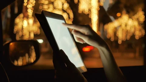 Woman using touchscreen on ipad mini in car during night with defocus road .. Video stock 236740892