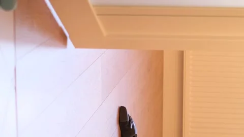 A woman using a vacuum cleaner while cleaning the floor of the house. Vertical Stock Footage 250354605
