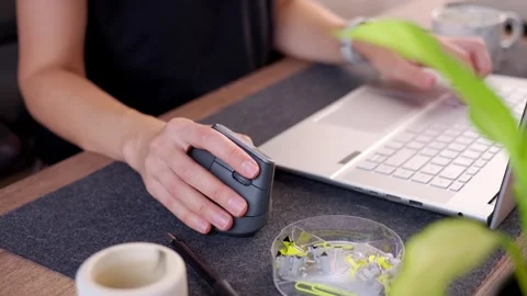 Woman using vertical ergonomic mouse and typing on laptop at desk Stock Footage 346653908
