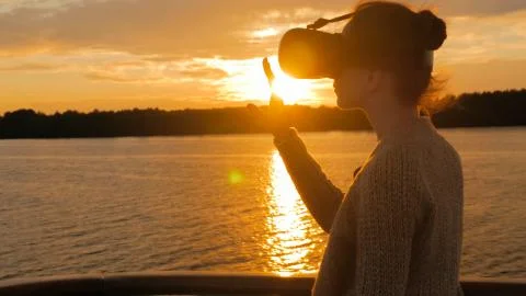 Woman using virtual reality glasses on deck of cruise ship at sunset Stock Photos
