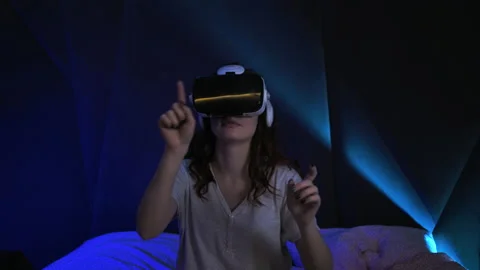 Woman Using Virtual Reality Headset Sitting on The Bed Looking Around. Future VR Stock Footage 160537014