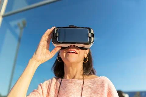 Woman using VR glasses while standing against building Fotos de archivo