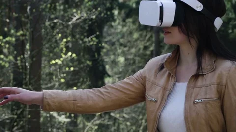 Woman using vr headset and exploring virtual reality in forest Stock Footage 74758882