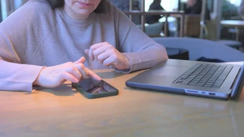 A woman is utilizing her smartphone while seated at a contemporary modern Video stock 305863912