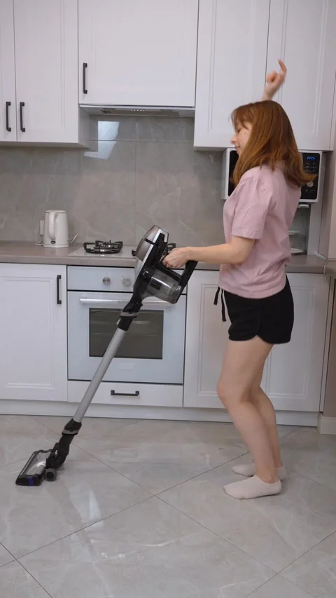 Woman vacuuming kitchen floor while dancing 스톡 동영상 314622390