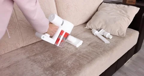 Woman is vacuuming sofa with velor upholstery. Stock Footage