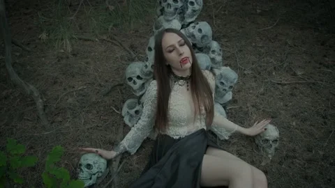 Woman vampire, false fangs. dark gothic forest scenery of human skulls. Stock Footage 140185576